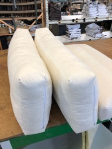 3 rectangle pillows with zip on workbench. Baffle stitching can be seen on third pillow lying on bench.
