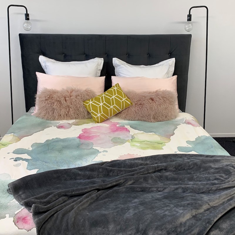 Charcoal button headboard with floral duvet pink, white and green throw pillows and grey throw