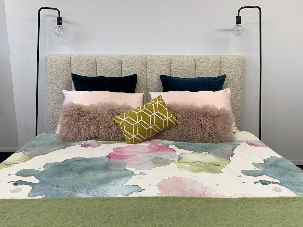 Vertical headboard in wool upholstery with floral duvet, green throw and navy, pink and green throw pillows