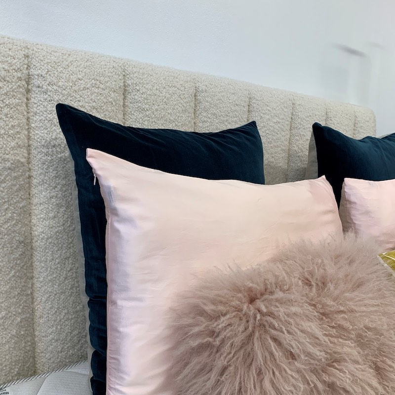 Headboard in woollen upholstery with navy and pink throw pillows