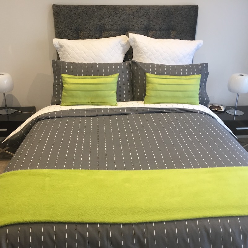Grey Button Headboard with grey duvet, green throw and cushions