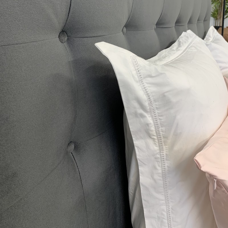 Close up of button headboard with white and pink pillows